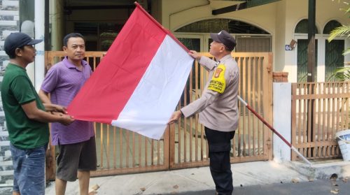 Polisi dari Polsek Grogol Petamburan membagikan bendera Merah Putih kepada warga di pinggir jalan untuk menyambut Hari Kemerdekaan ke-80 Republik Indonesia.