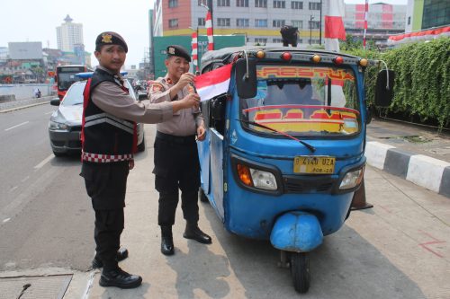 Petugas Polsek Metro Tamansari membagikan bendera merah putih kepada warga di Jakarta Barat