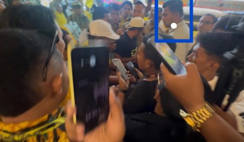 Seorang pria yang diduga ajudan menteri (ditandai kotak biru) berada di tengah kerumunan wartawan saat sesi wawancara di Musda Golkar Maluku Utara di Ternate.