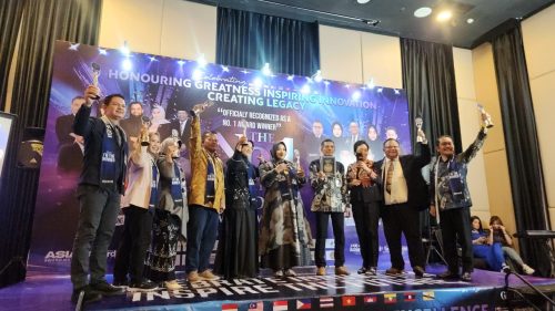 Sejumlah penerima penghargaan berdiri di atas panggung sambil mengangkat trofi dalam acara penganugerahan bertema kepemimpinan dan inovasi di sebuah hotel.